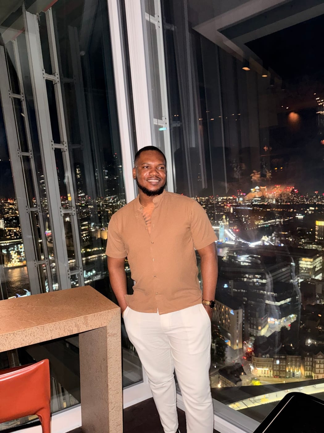 Tochii Achebe at the Shard, with London at night behind him